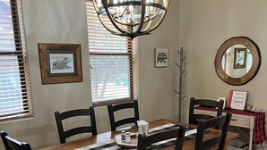 Un coin repas avec une table en bois, des chaises noires, un lustre et des tableaux encadrés accrochés aux murs.