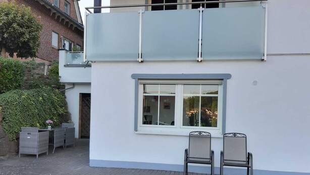 Un bâtiment à deux étages doté d’un balcon, d’une fenêtre offrant une belle vue et d’un espace extérieur aménagé pour s’asseoir.
