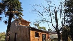 A wooden cabin with a balcony, surrounded by trees and a clear sky. - Villa Les Hibiscus - 500m from the beach - authentic style and design for 8 (Longeville-sur-Mer)