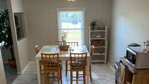 A dining area with a table and chairs, a potted plant, and a window with a view. - Camp Coastal Escape with perks and discounts!! (Jacksonville)