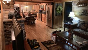 Interior acollidor d'una cabana amb zona de menjador, cuina i saló.