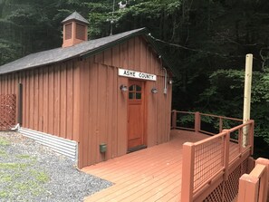 A wooden cabin with a sign reading "Ash County" and a wooden deck with a railing.