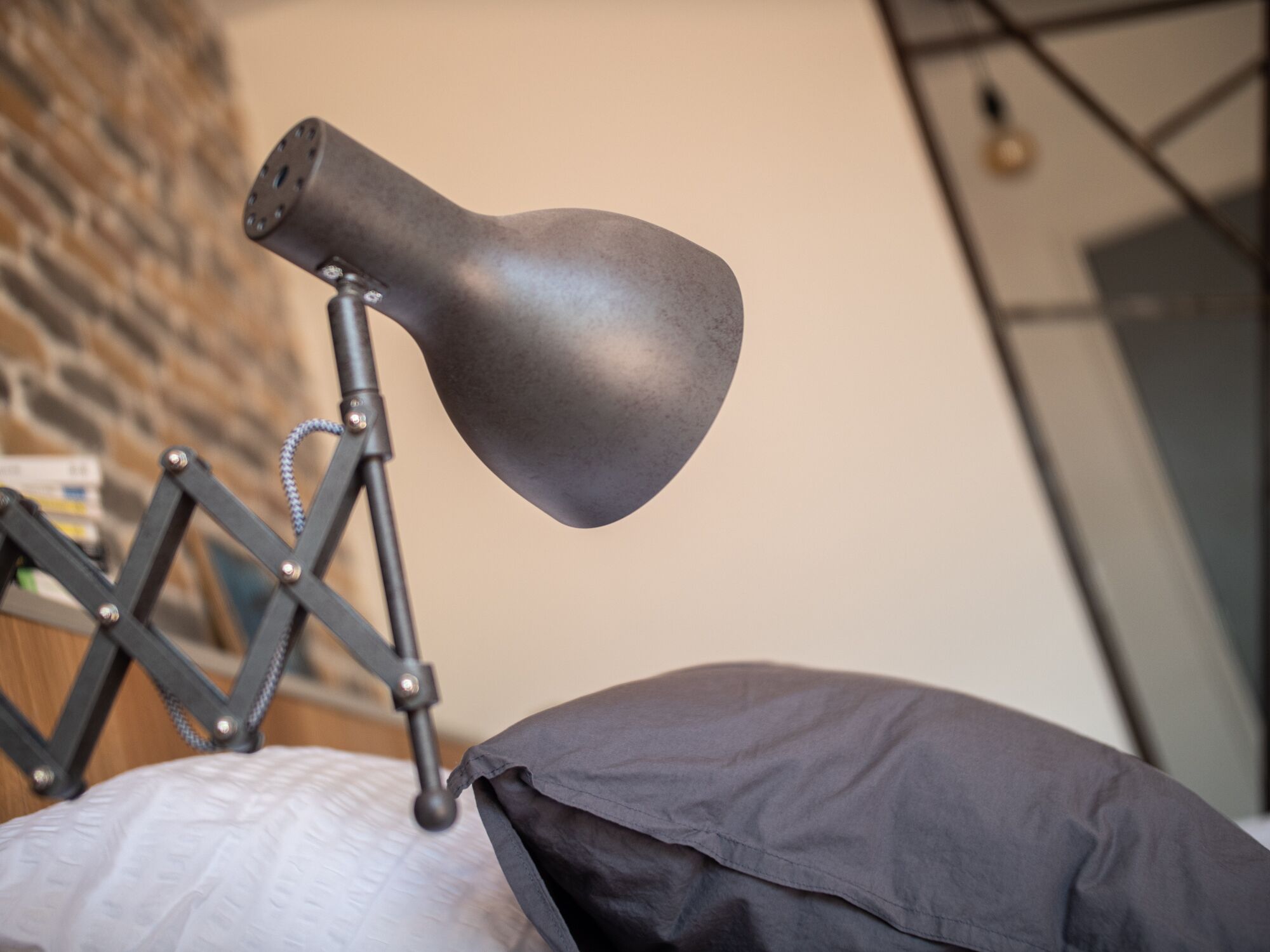 A modern lamp on a desk with a geometric metal frame and a black lampshade.