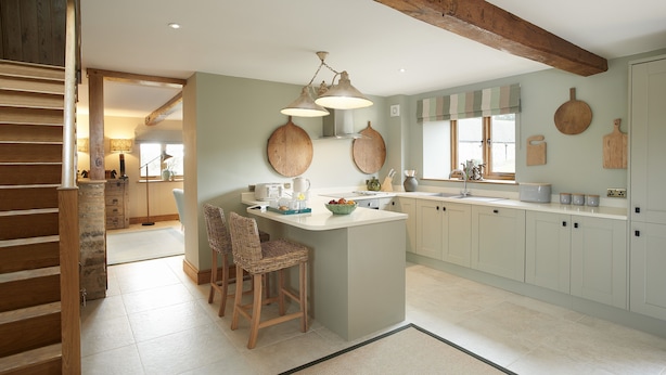 A kitchen with a central island, wooden chairs, and a hanging light fixture. - The Stone Barn is a romantic and restorative barn conversion for adults (Downton-on-the-Rock)