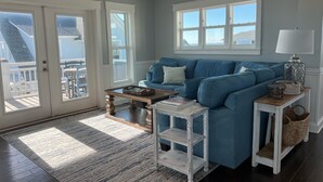 A living room with a blue sofa, a coffee table, and a small white side table. - Ocean View - Family Friendly - Steps to Beach (Bald Head Island)