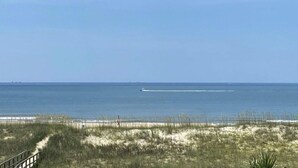 A beach with a clear sky and a sandy path leading to the water. - Ocean View - Family Friendly - Steps to Beach (Bald Head Island)