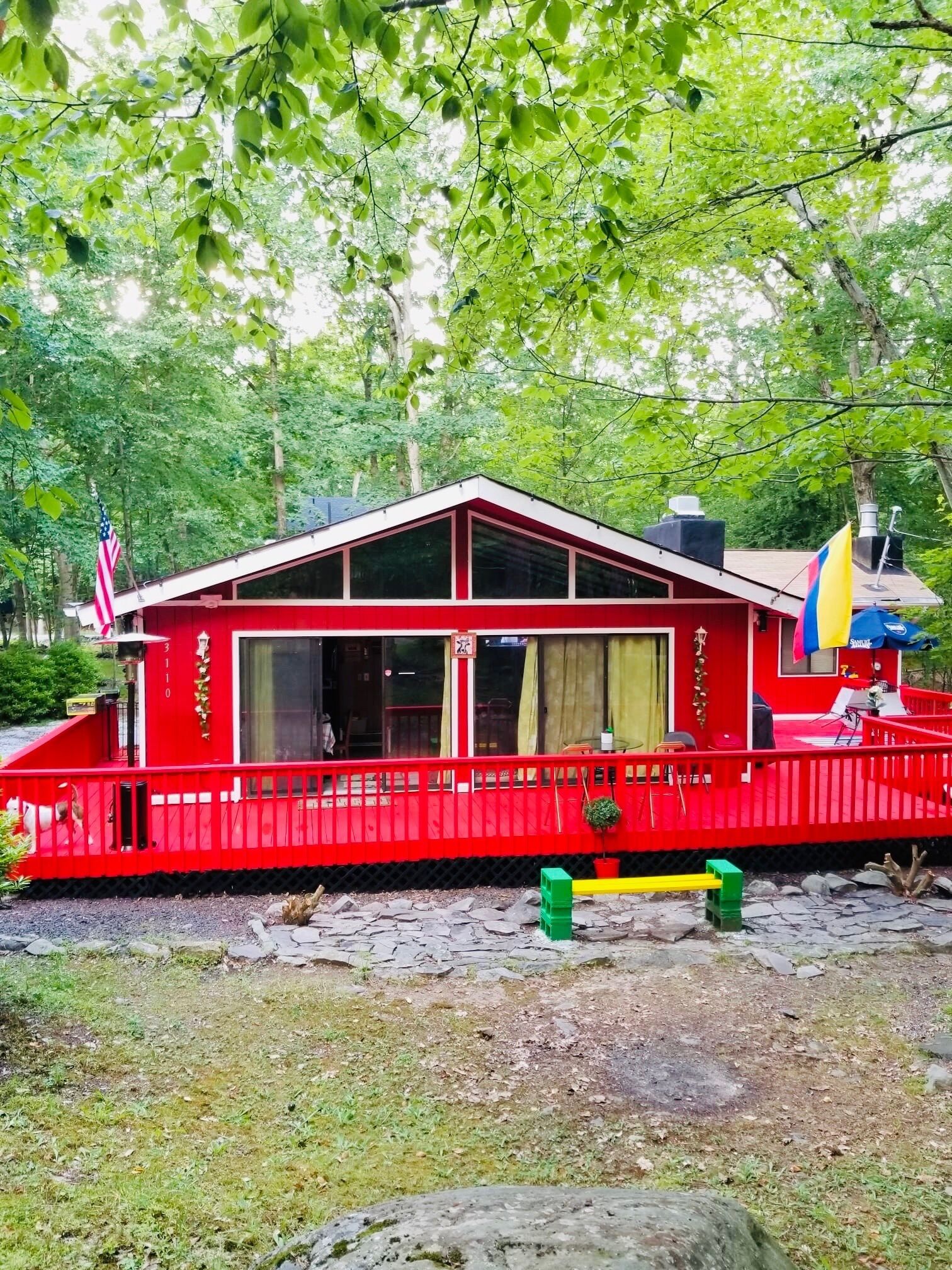 A red cabin with a white roof, surrounded by trees.