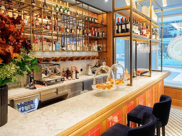 A bar area with shelves of bottles, a coffee machine, and a display of pastries.