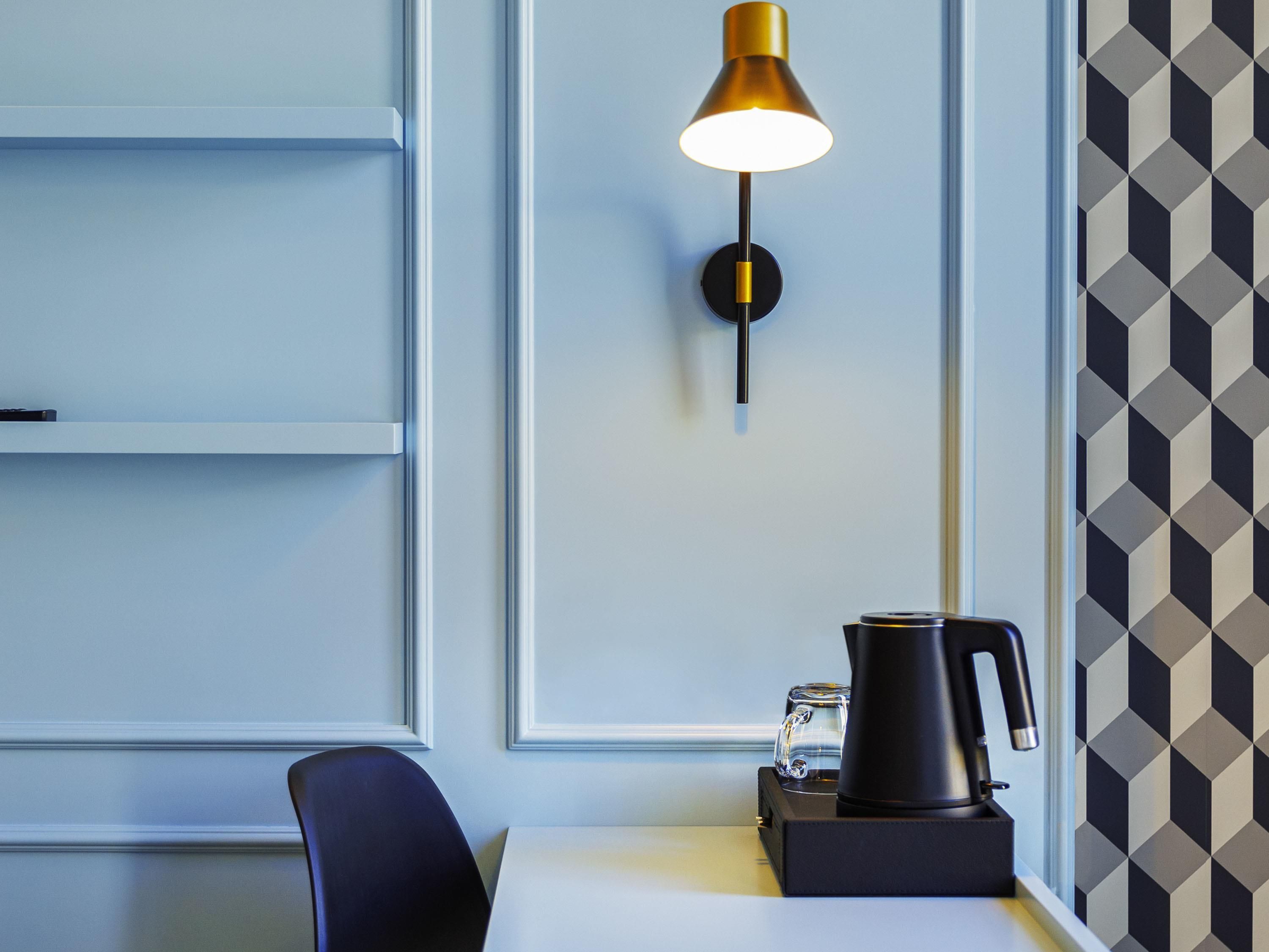 Quarto moderno com design minimalista, com luminária de parede, cafeteira e uma cadeira.