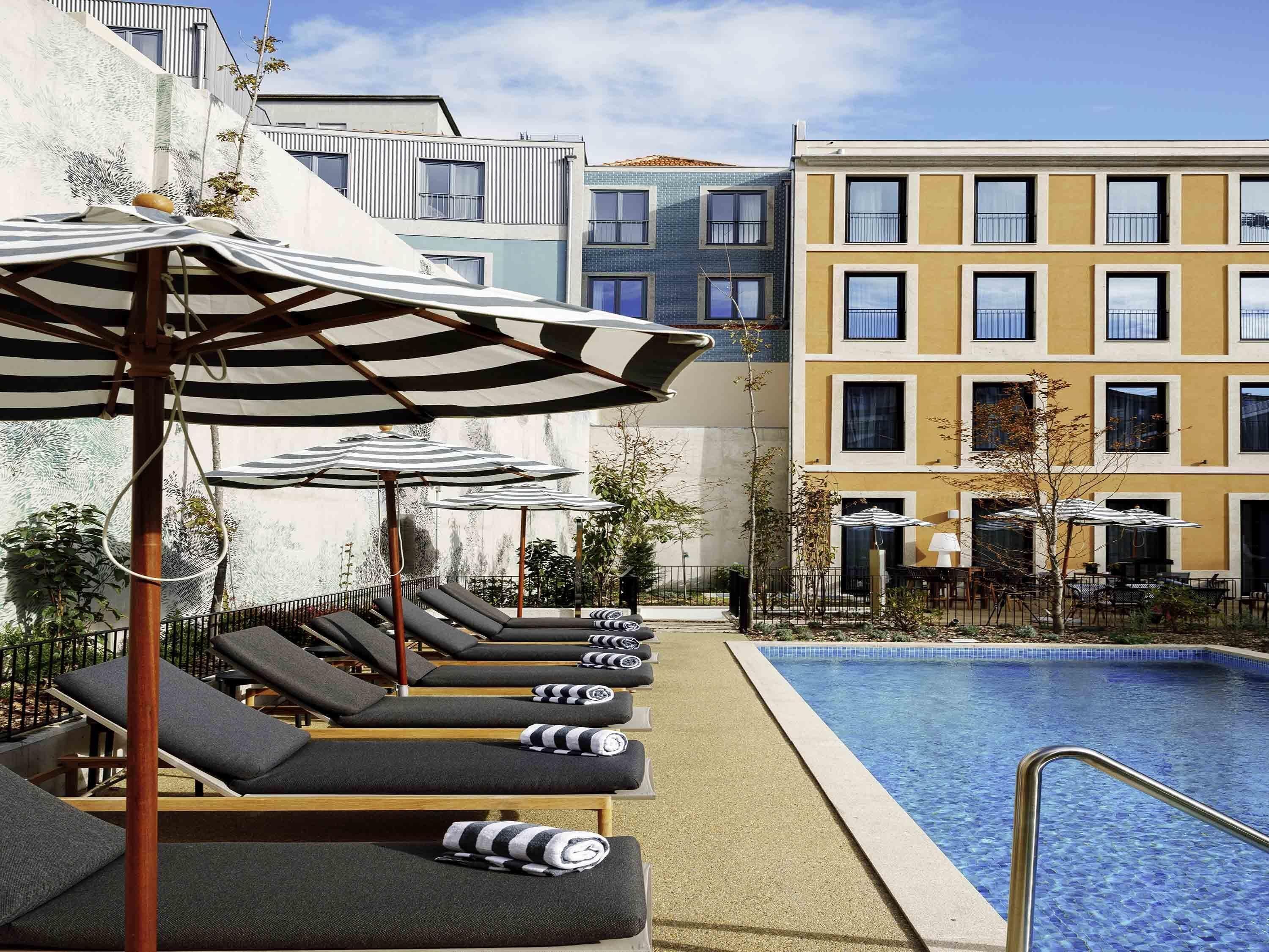 Una piscina al aire libre, sombrillas, tumbonas