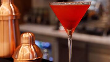 A martini glass with a red cocktail on a bar counter.