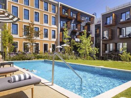 Una piscina al aire libre, sombrillas, tumbonas