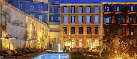 Una piscina al aire libre, sombrillas, sillones reclinables de piscina