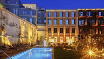 Una piscina al aire libre, sombrillas, sillones reclinables de piscina