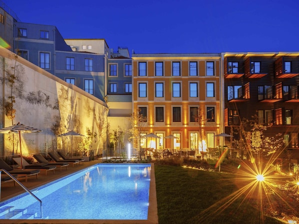 Alberca al aire libre, sombrillas en la alberca y camastros