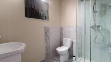 Un baño moderno con ducha acristalada, inodoro blanco y lavabo.
