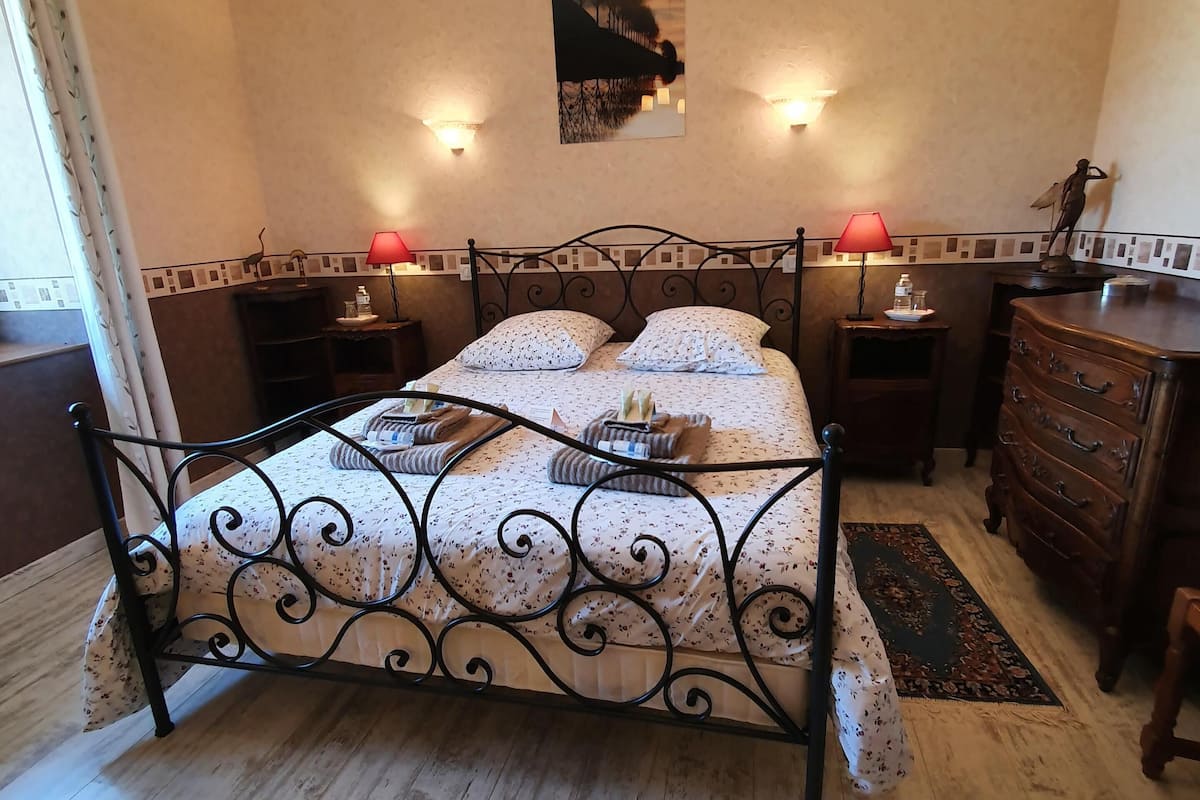 Een slaapkamer met een hemelbed, twee nachtkastjes, een kaptafel en een kroonluchter.