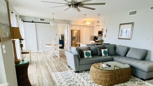 A spacious living room with a large gray sectional sofa, a round coffee table, and a patterned rug.