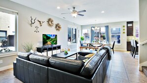 Un salon moderne avec un canapé en cuir, un téléviseur à écran plat et des œuvres d’art décoratives accrochées au mur.