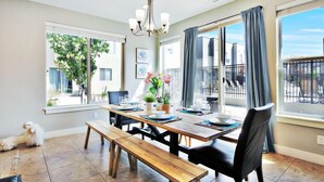 Un coin repas avec une table en bois, des bancs et des chaises. Un lustre est suspendu au-dessus de la table.