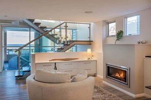 Un interior moderno con chimenea, un sofá y una escalera que conduce a un espacio exterior.
