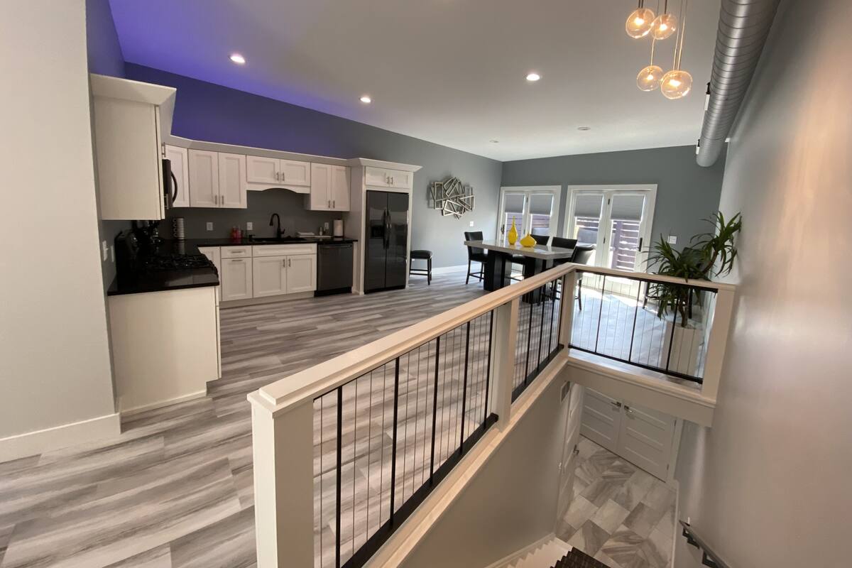 A modern kitchen with white cabinets, a stainless steel refrigerator, and a dining area with a table and chairs.
