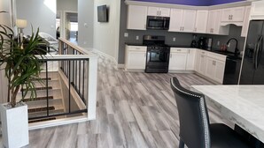 A modern kitchen with white cabinets, a black refrigerator, and a stainless steel oven. - The Flatts at North Shore (Geneva)