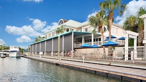 A waterfront hotel with a covered deck, palm trees, and a boat dock. - Pecan Paradise: near Beach & Downtown! (Wilmington)