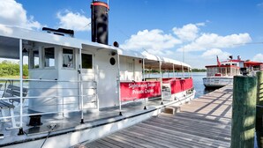 A boat docked at a pier with a sign advertising sightseeing sunset private cruises. - Pecan Paradise: near Beach & Downtown! (Wilmington)