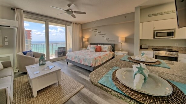 A hotel room with a bed, a desk, a chair, a balcony, and a kitchenette. - Deluxe Beachfront  Studio,  Great Views, "Shores of Panama", Remodeled,  A/C (Panama City Beach)