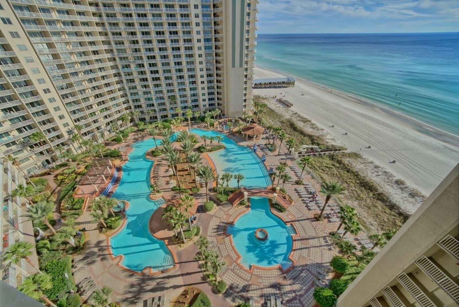 Ein Resort mit mehreren Schwimmbecken, umgeben von Palmen und einem Strand.