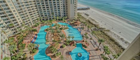 Un resort con varias piscinas rodeado de palmeras y una playa.