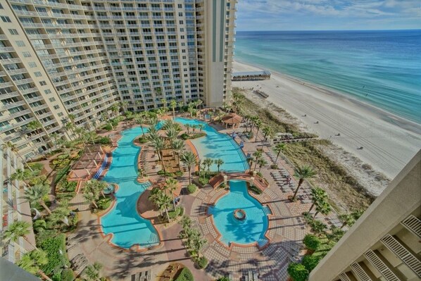 A resort with multiple swimming pools surrounded by palm trees and a beach.