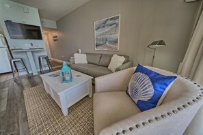 A living room with a sofa, a coffee table, a lamp, and a painting on the wall.