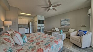 A hotel room with a bed, a sofa, a TV, a ceiling fan, and a kitchenette. - Deluxe Beachfront  Studio,  Great Views, "Shores of Panama", Remodeled,  A/C (Panama City Beach)