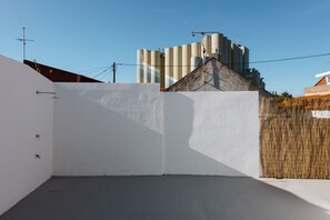 A rooftop terrace with a white wall and a bamboo fence. - Beach, Surfing, and the City - 1-Bedroom Villa (Trafaria)