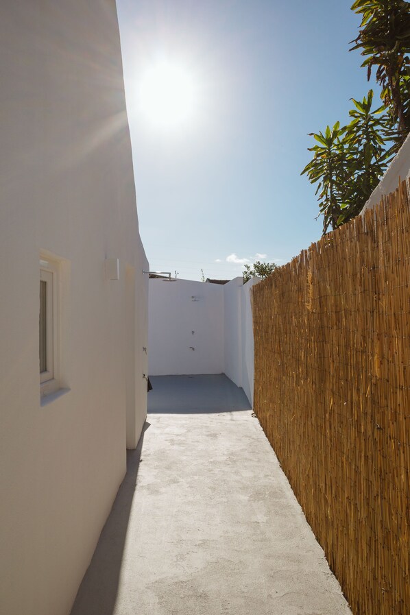 A narrow concrete pathway leading to a white building with a window and a wooden fence. - Beach, Surfing, and the City - 1-Bedroom Villa (Trafaria)