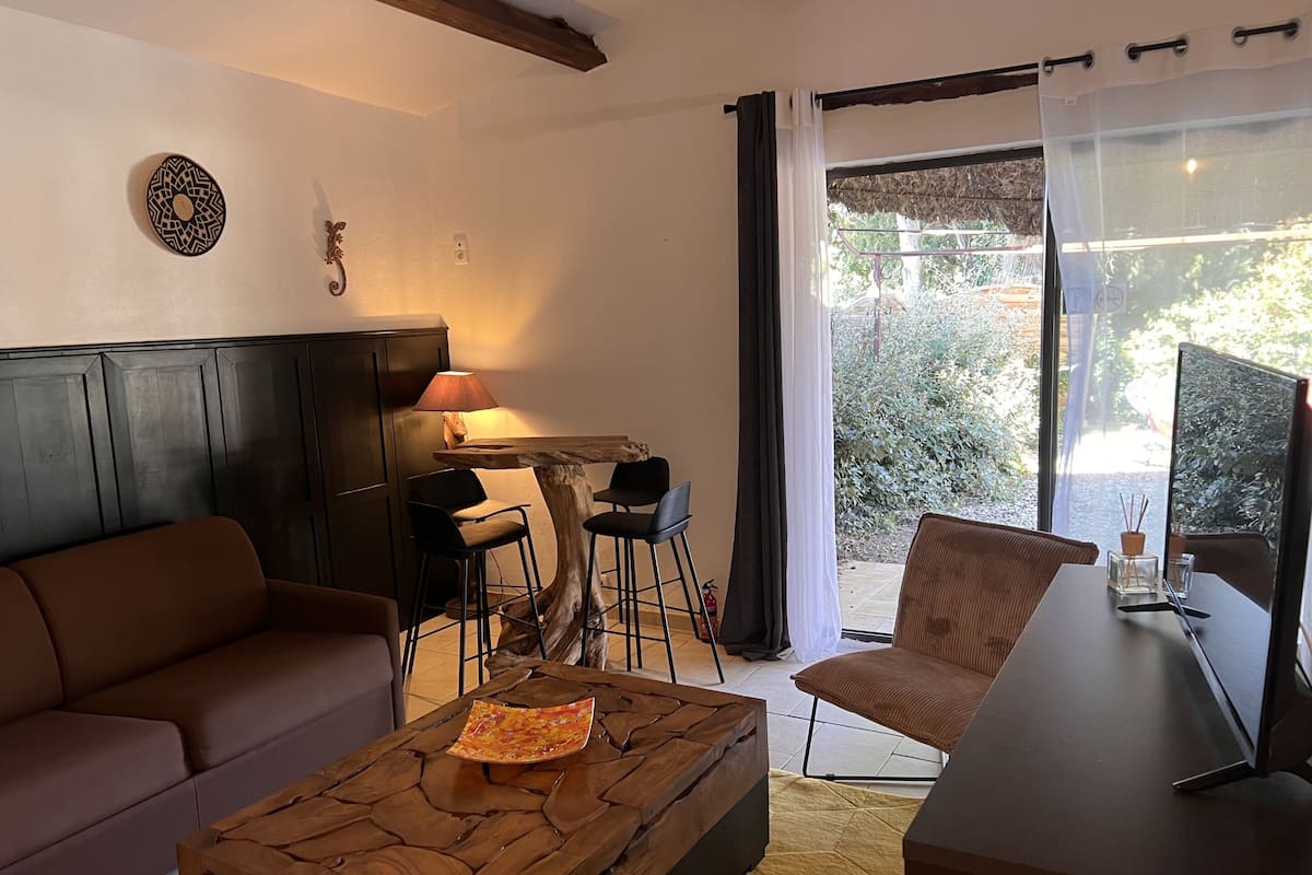 A living room with a brown sofa, a wooden coffee table, and a dining area with a table and chairs.
