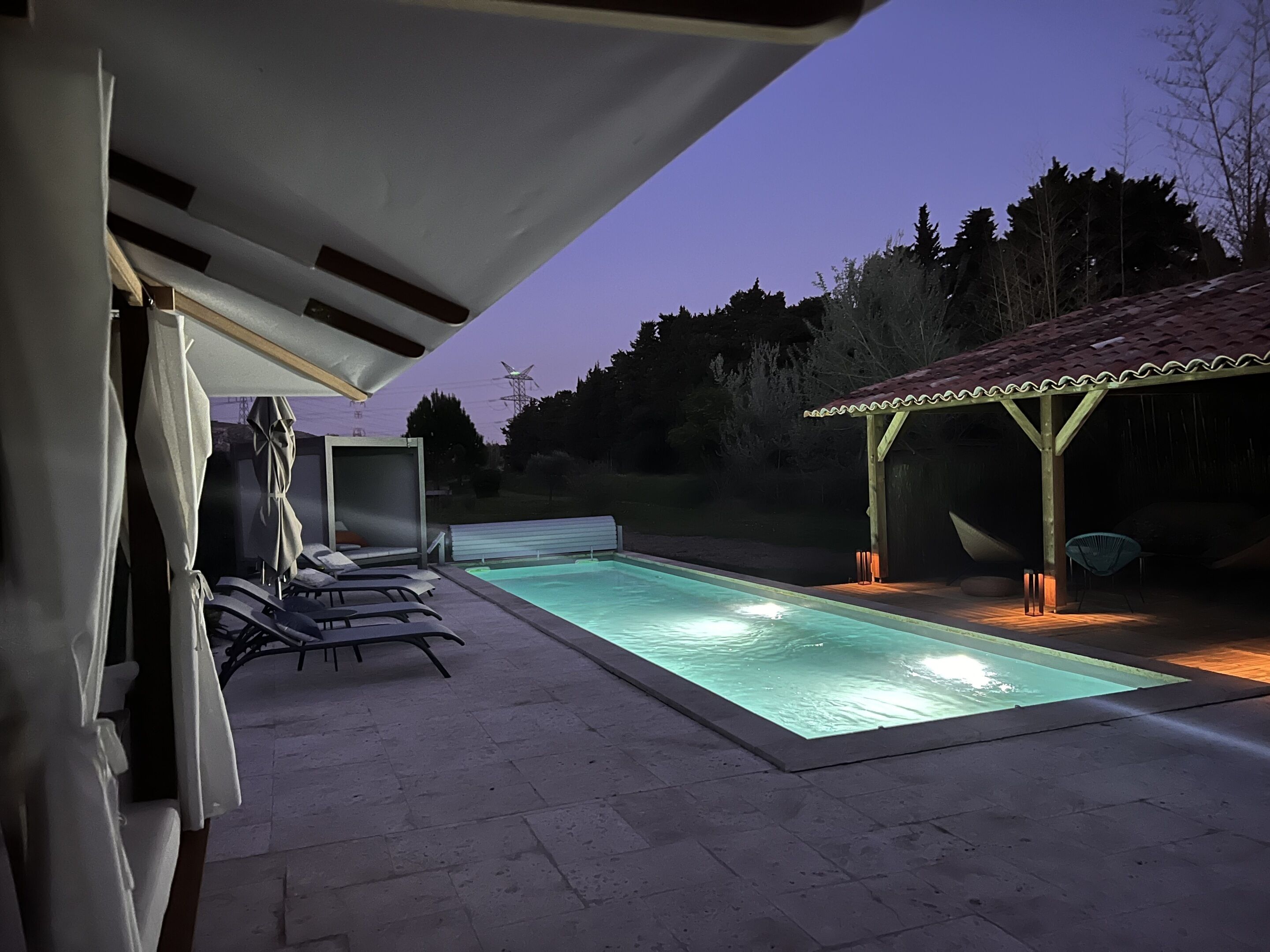 Una piscina con sillas de descanso, una zona de estar cubierta y un pabellón.