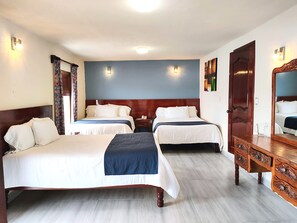 A hotel room with two beds, a wooden dresser, and a mirror.