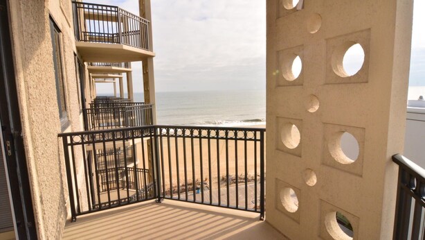 Een balkon met uitzicht op strand en zee.