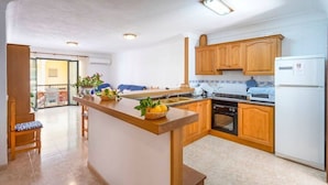 A kitchen with wooden cabinets, a central island with a bowl of lemons, a built-in oven, and a refrigerator. - M0 Large apartment of 100 m2 + terraces (Sant Jordi)