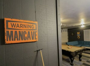 Una mesa de billar en una sala con un letrero de advertencia en la pared.