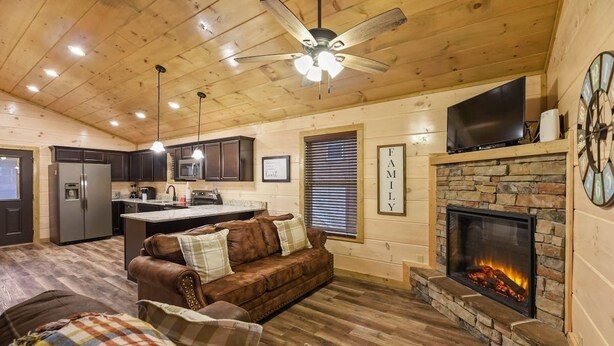 Un interior acogedor de cabaña con sala de estar, cocina y chimenea.