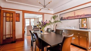 A dining area with a dark wooden table, chairs, a vase with flowers, and a kitchen area with cabinets and a countertop. - Golden Gate Park 4BR Home | Garage + Metro Access (San Francisco)