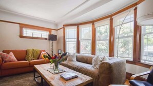 A cozy living room with a wooden coffee table, a sofa, and a loveseat. - Golden Gate Park 4BR Home | Garage + Metro Access (San Francisco)