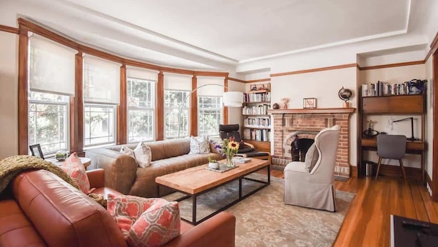 A cozy living room with a leather sofa, a wooden coffee table, and a fireplace. - Golden Gate Park 4BR Home | Garage + Metro Access (San Francisco)