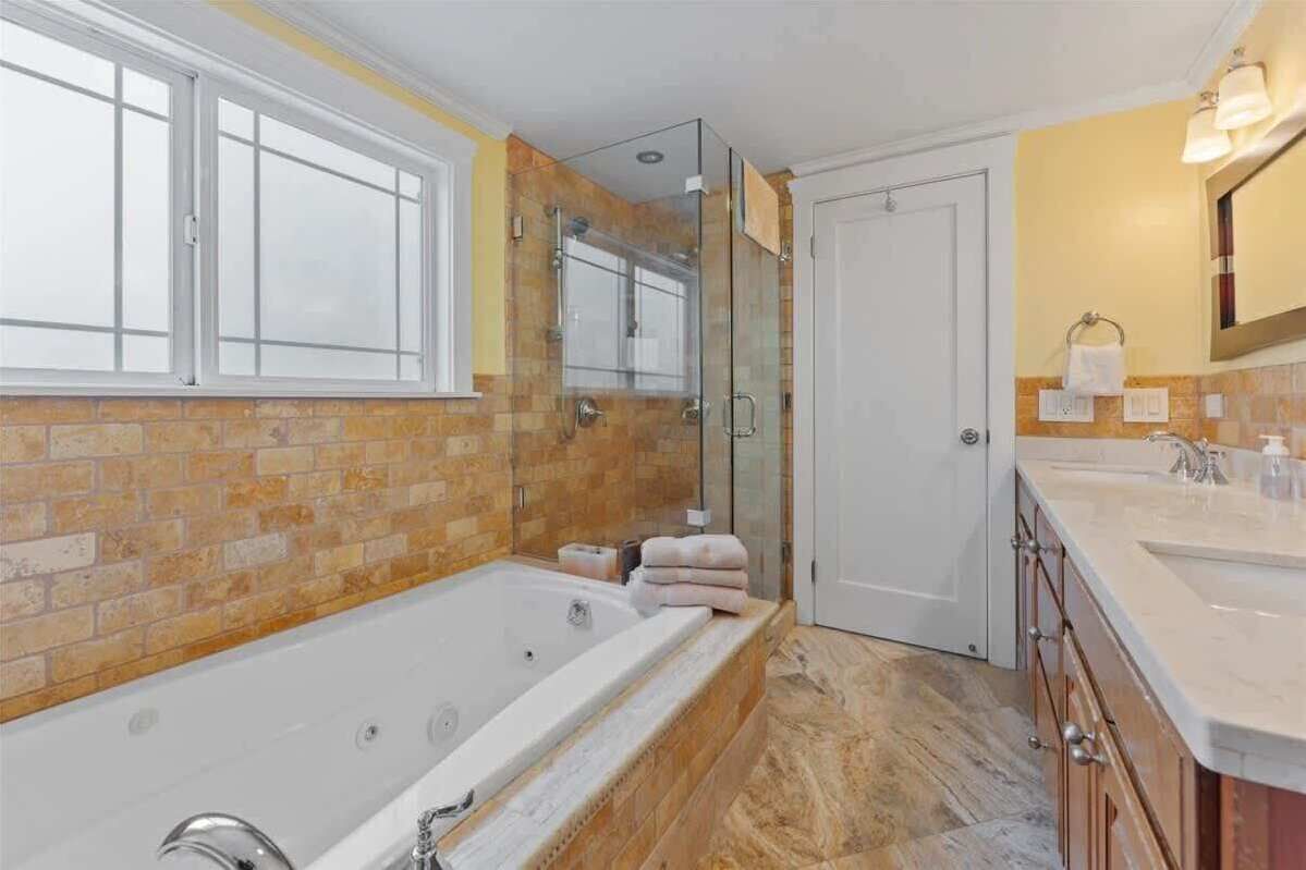 Un baño moderno con una bañera grande, una ducha con cerramiento de vidrio y un tocador doble.