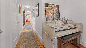 A hallway with a piano and a poster on the wall. - Golden Gate Park 4BR Home | Garage + Metro Access (San Francisco)