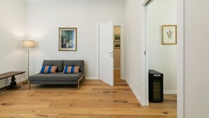 A room with a grey sofa, a lamp, a framed painting, and a computer on a wooden floor. - GuestHost - Elegant Don Giovanni flat of 60 sqm, for 4 people, located on the 5th floor of a historic building in Via Principe di Belmonte: NotHotel, a luxury Guest House, equipped with every comfort. Once inside you will be greeted by an elegant environ (Palermo)